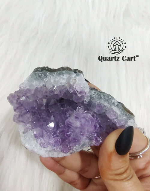Natural Amethyst crystal cluster medium #02 held in hand showing raw purple crystal points for healing and meditation.