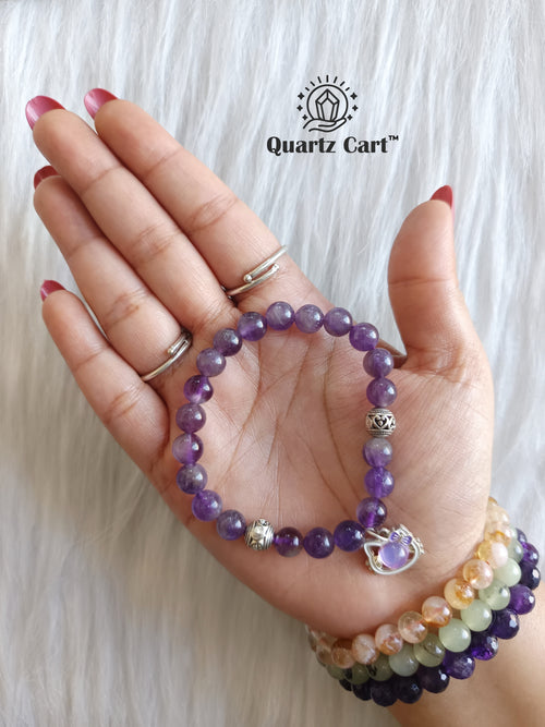 Hand holding Amethyst kids healing crystal bracelet for calmness protection and emotional balance