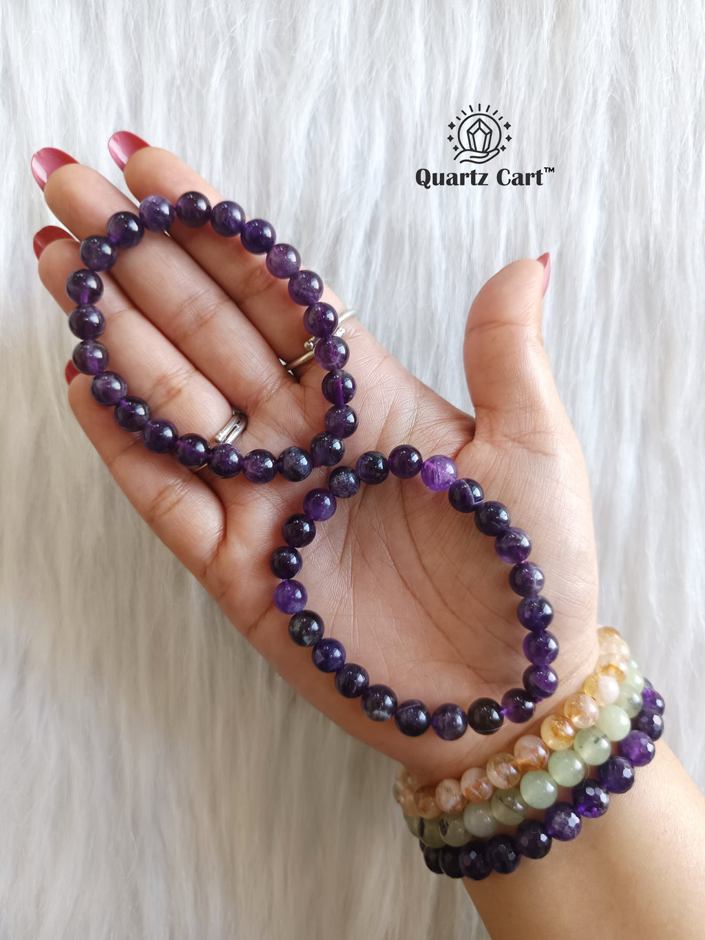 Hand holding Amethyst round healing crystal bracelet for calmness protection and emotional balance