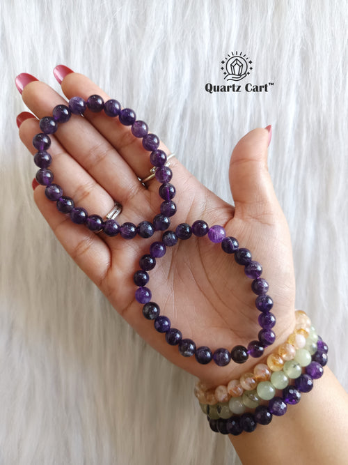 Hand holding Amethyst round healing crystal bracelet for calmness protection and emotional balance