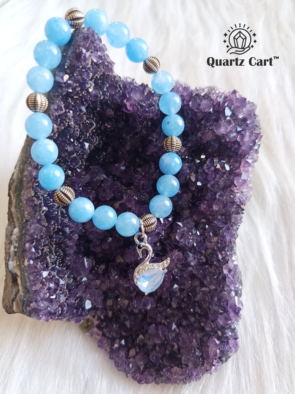 Aquamarine charms bracelet placed on crystal cluster with blue gemstone beads and charm, healing crystal bracelet for calm mind and communication