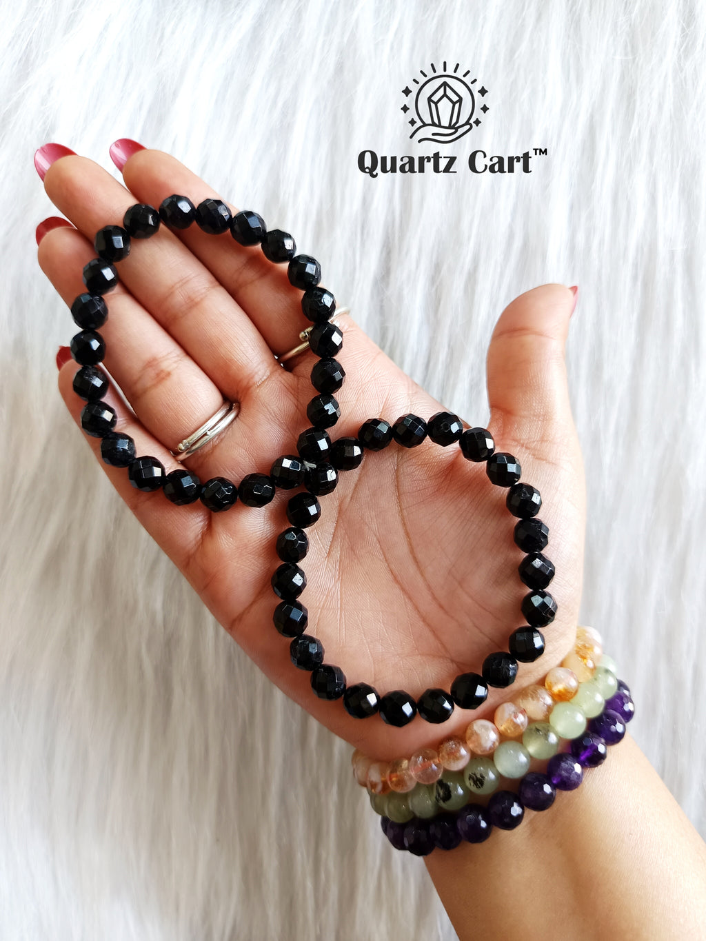Hand holding Black Tourmaline faceted healing crystal bracelet for protection grounding and energy shielding