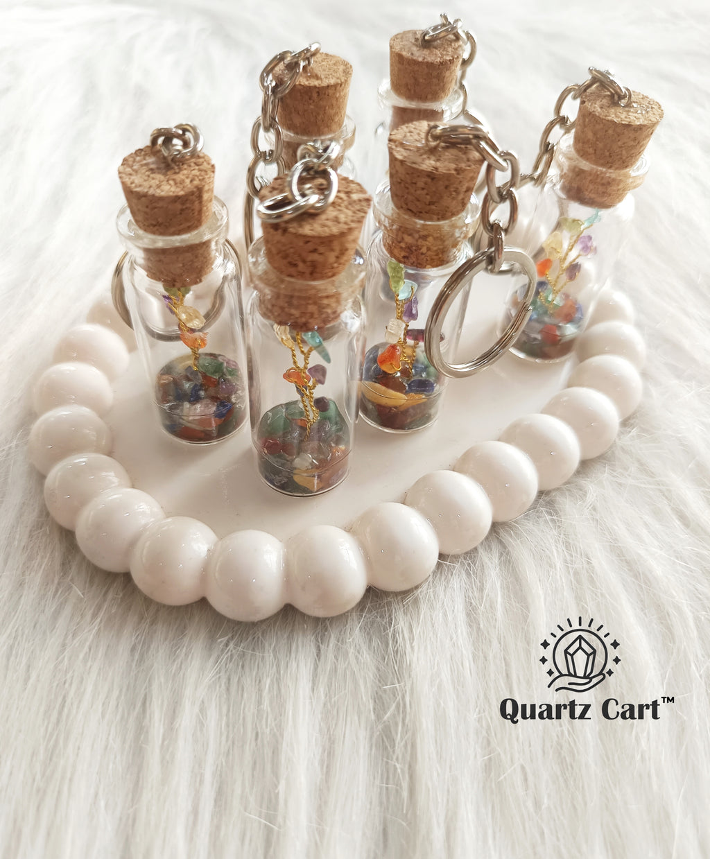 multiple bottle keychains with color stone chips on white surface