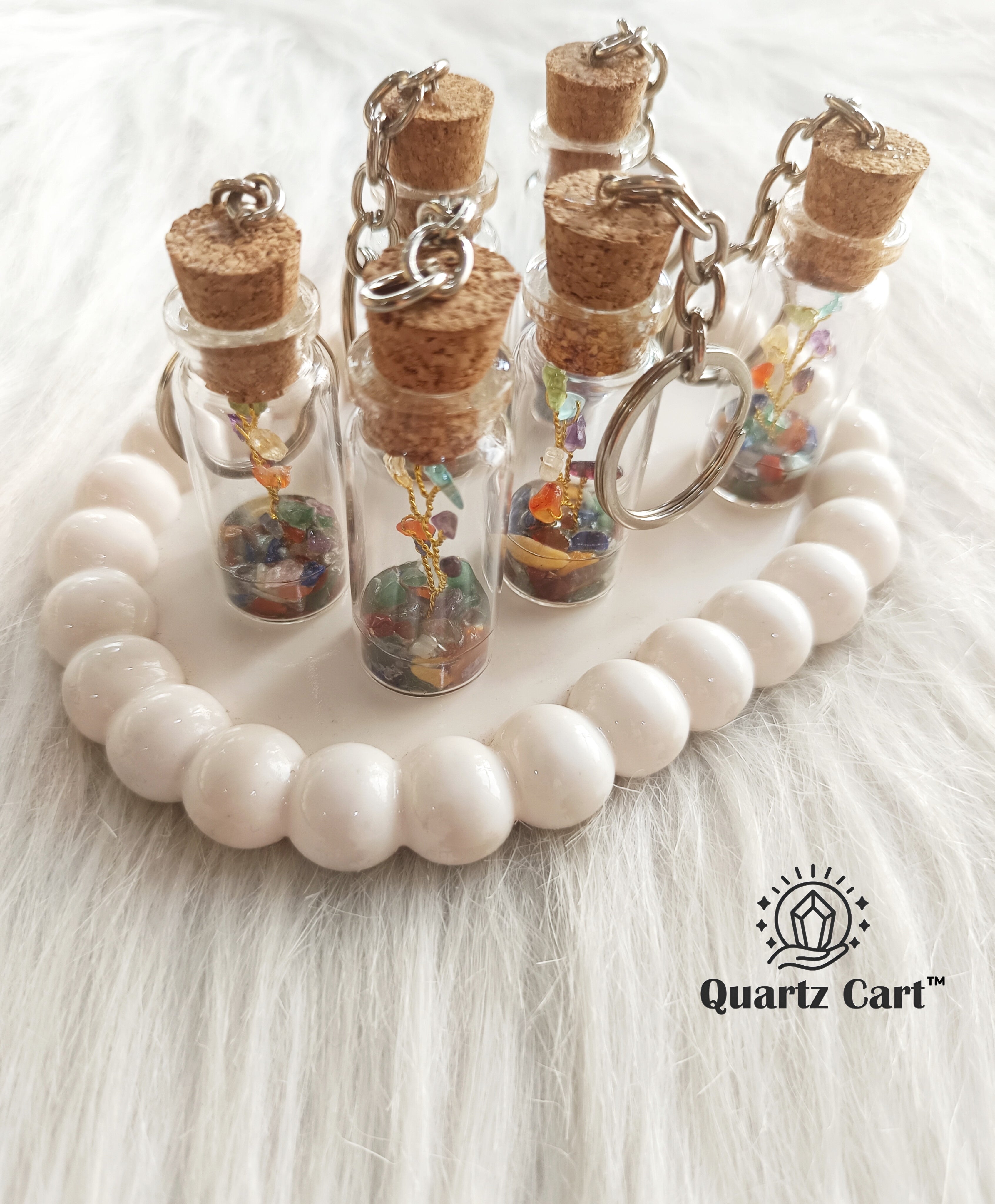 multiple bottle keychains with color stone chips on white surface