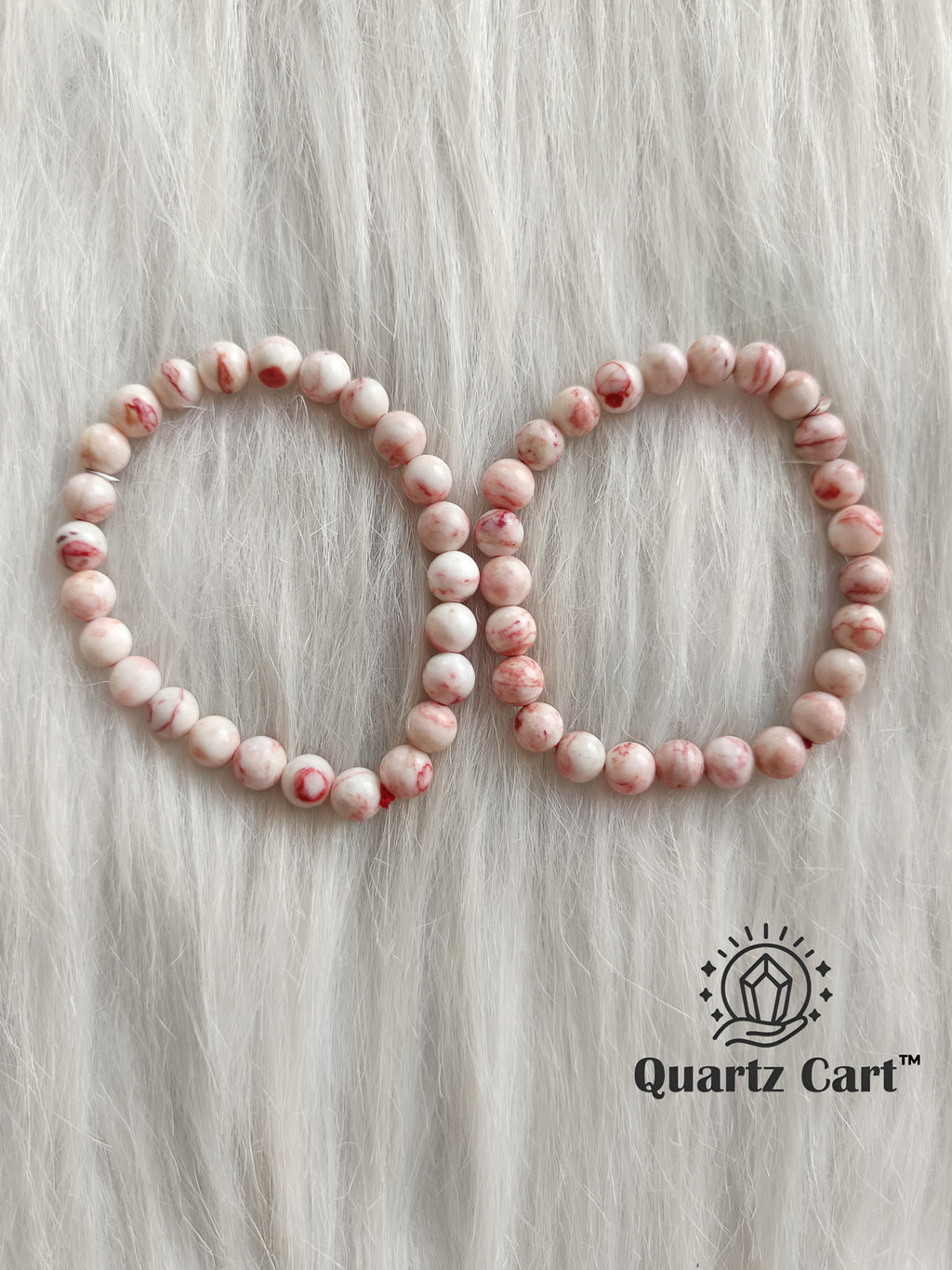 Two cinnabar bracelets displayed on soft surface showing natural red gemstone beads, crystal bracelet for wealth, prosperity and manifestation