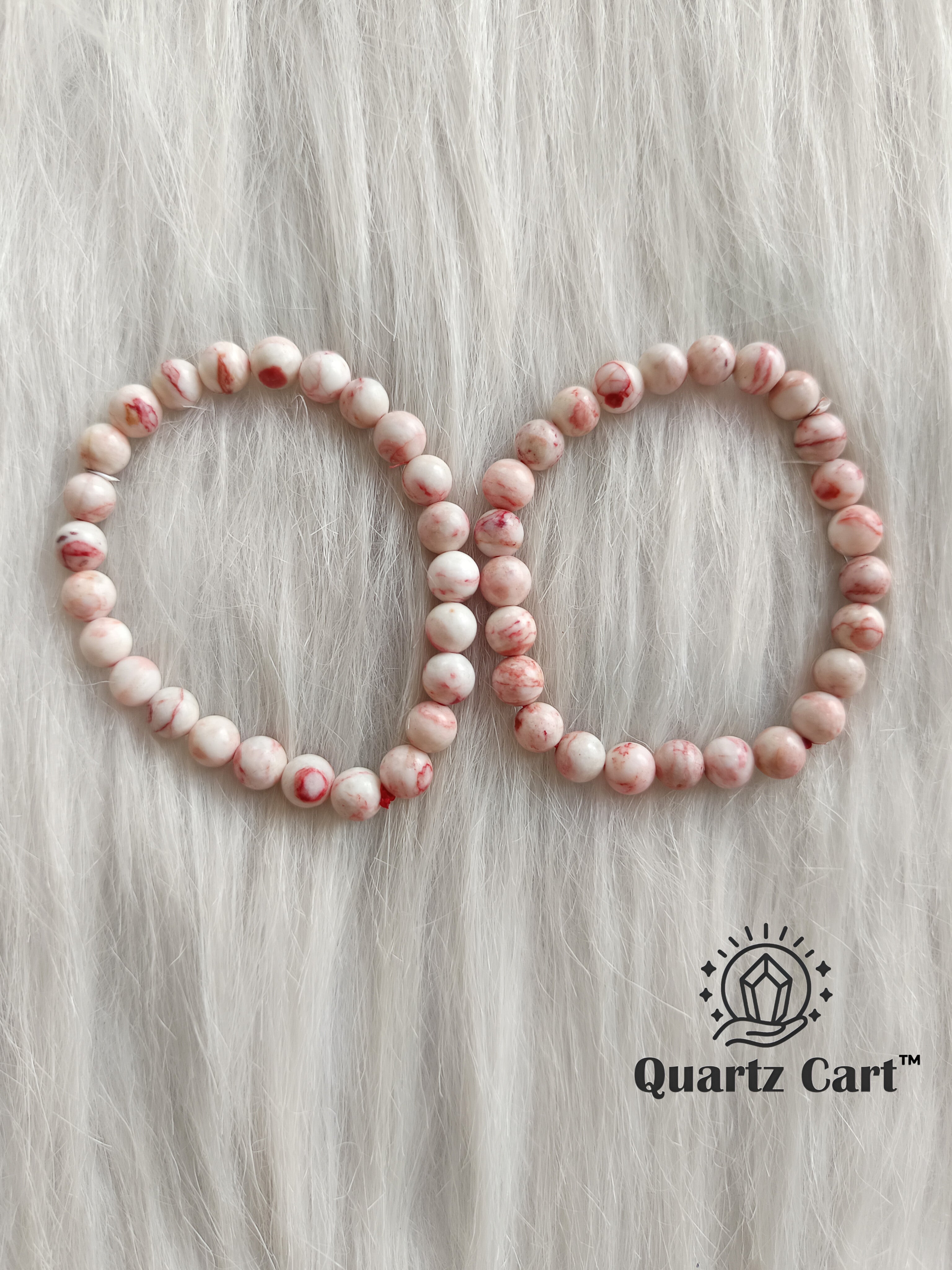 Two cinnabar bracelets displayed on soft surface showing natural red gemstone beads, crystal bracelet for wealth, prosperity and manifestation