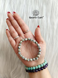 Natural Dalmatian Jasper bracelet with black spotted beads displayed on surface, healing crystal jewelry for positivity and protection