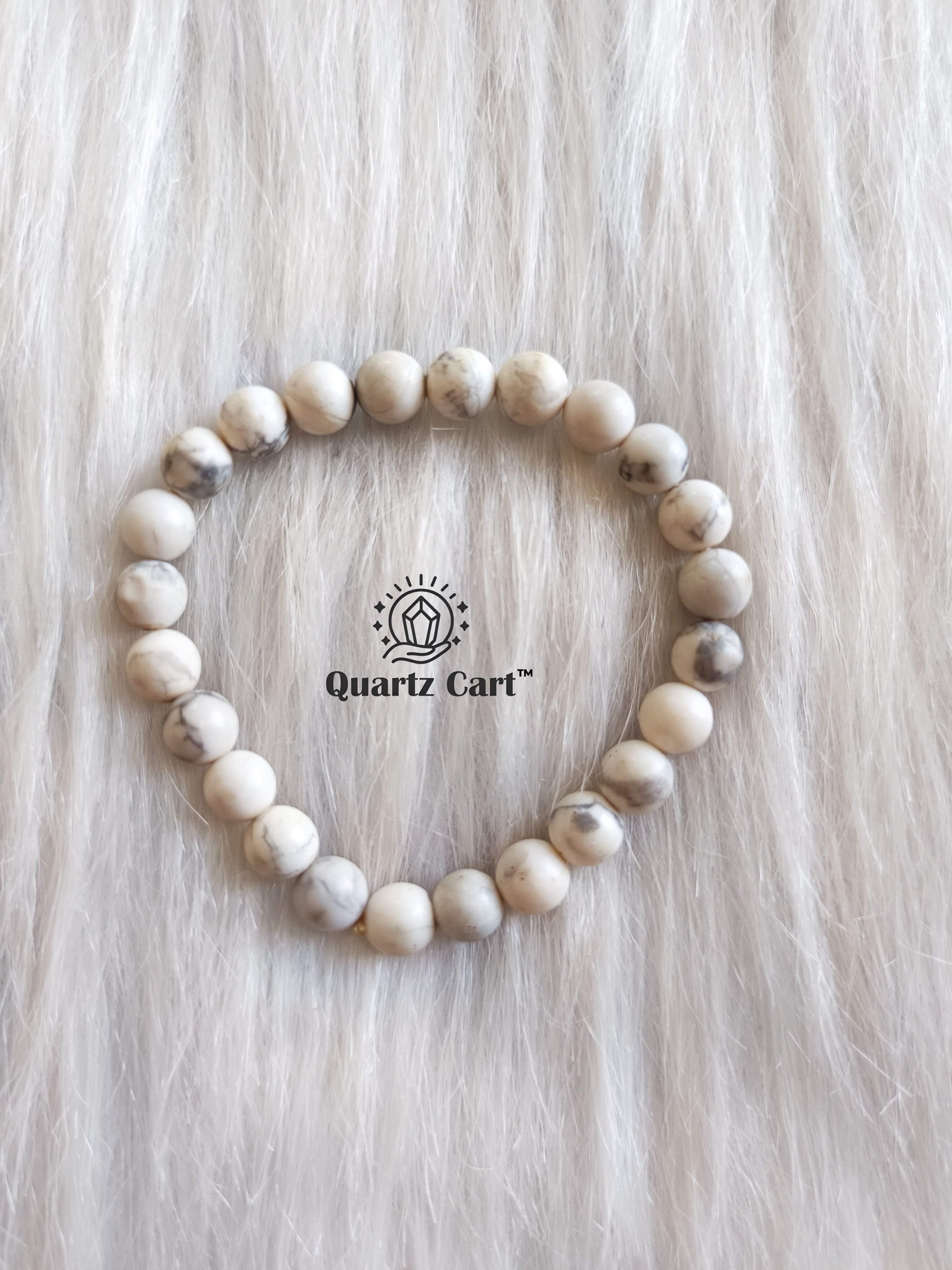 Howlite bracelet displayed on surface showing white gemstone beads with grey veins, healing crystal bracelet for calmness, stress relief and emotional balance