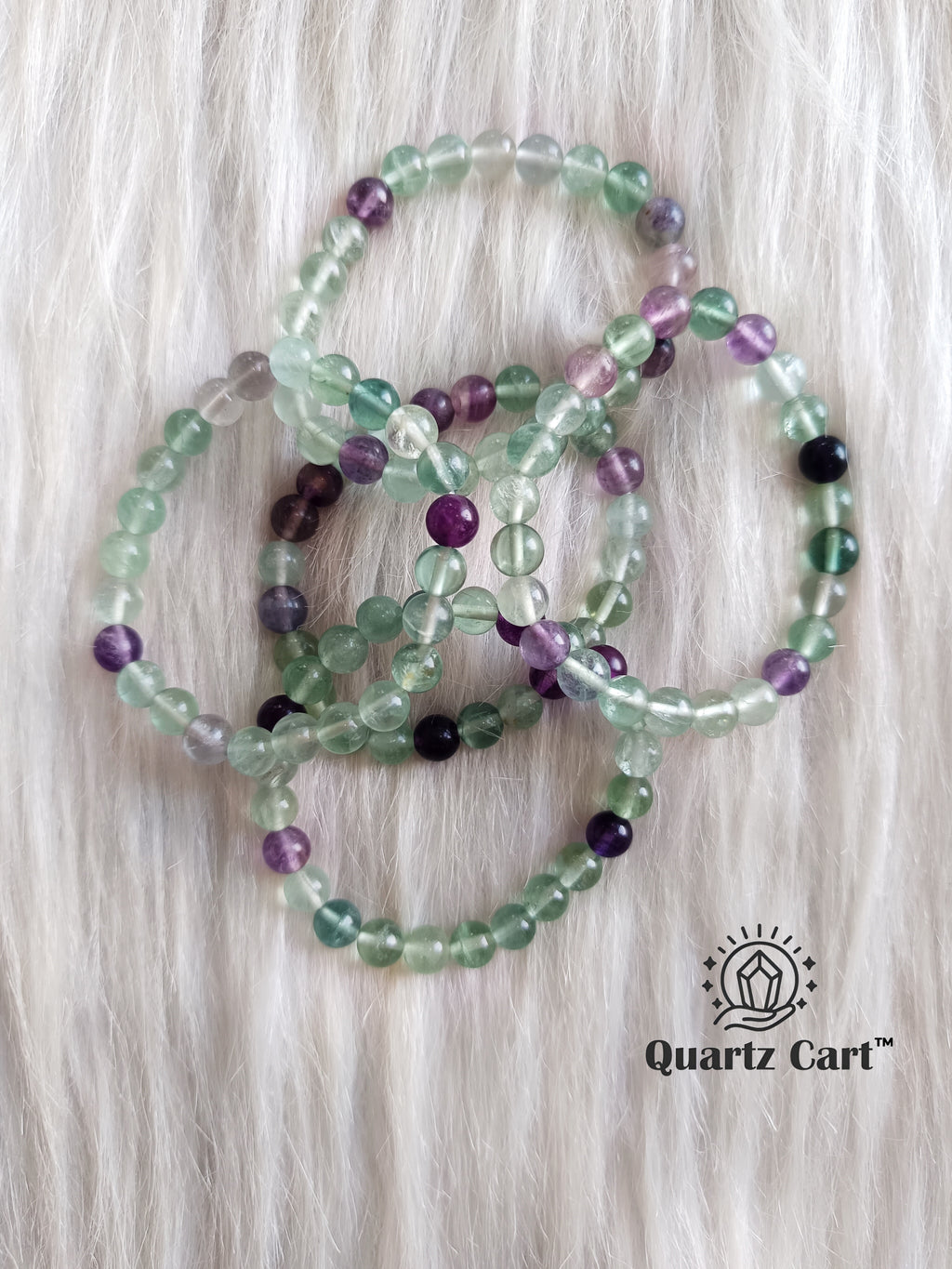 Multi fluorite bracelets displayed on soft surface showing green and purple gemstone beads, healing crystal bracelet for mental clarity and protection