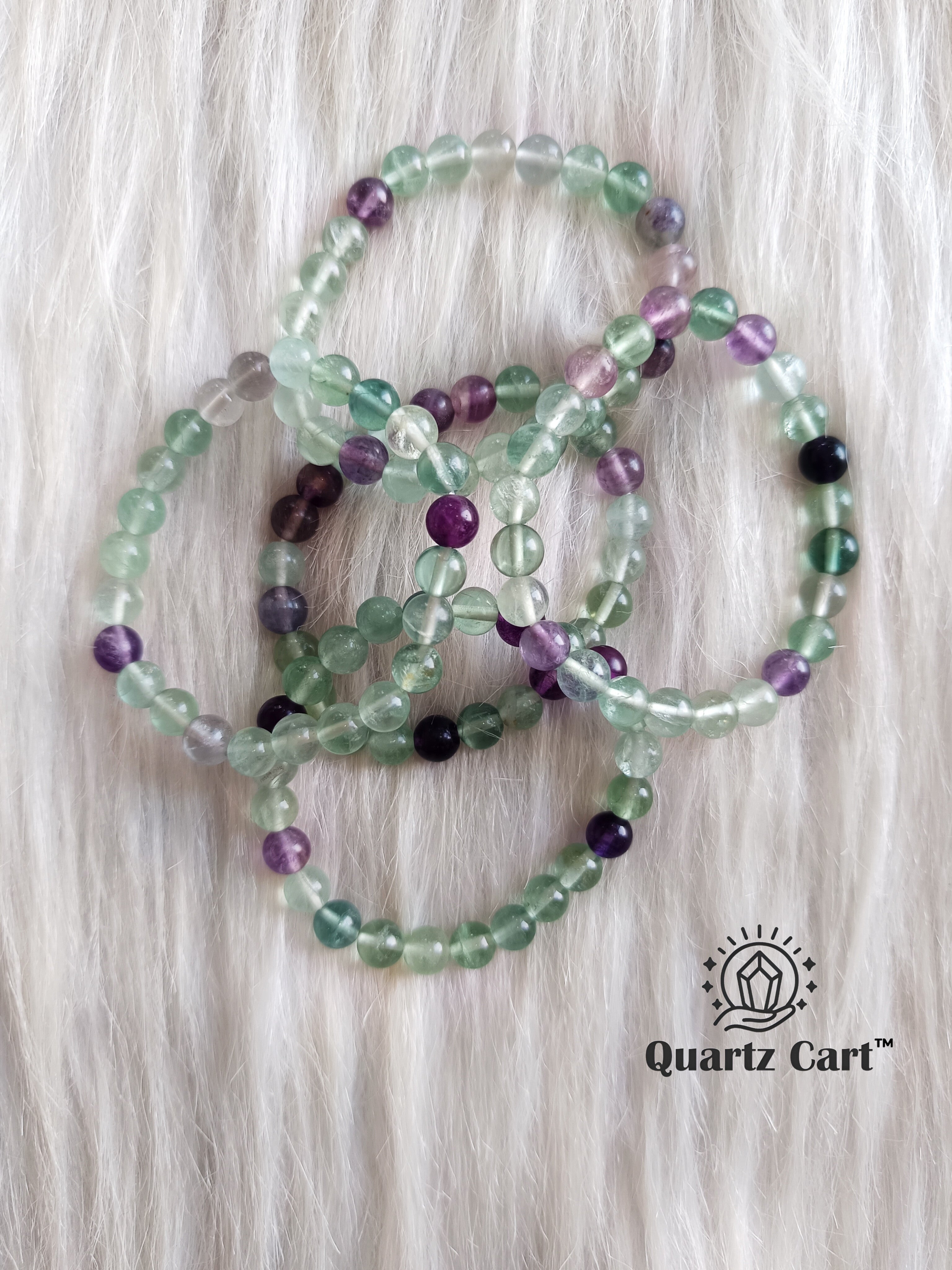 Multi fluorite bracelets displayed on soft surface showing green and purple gemstone beads, healing crystal bracelet for mental clarity and protection