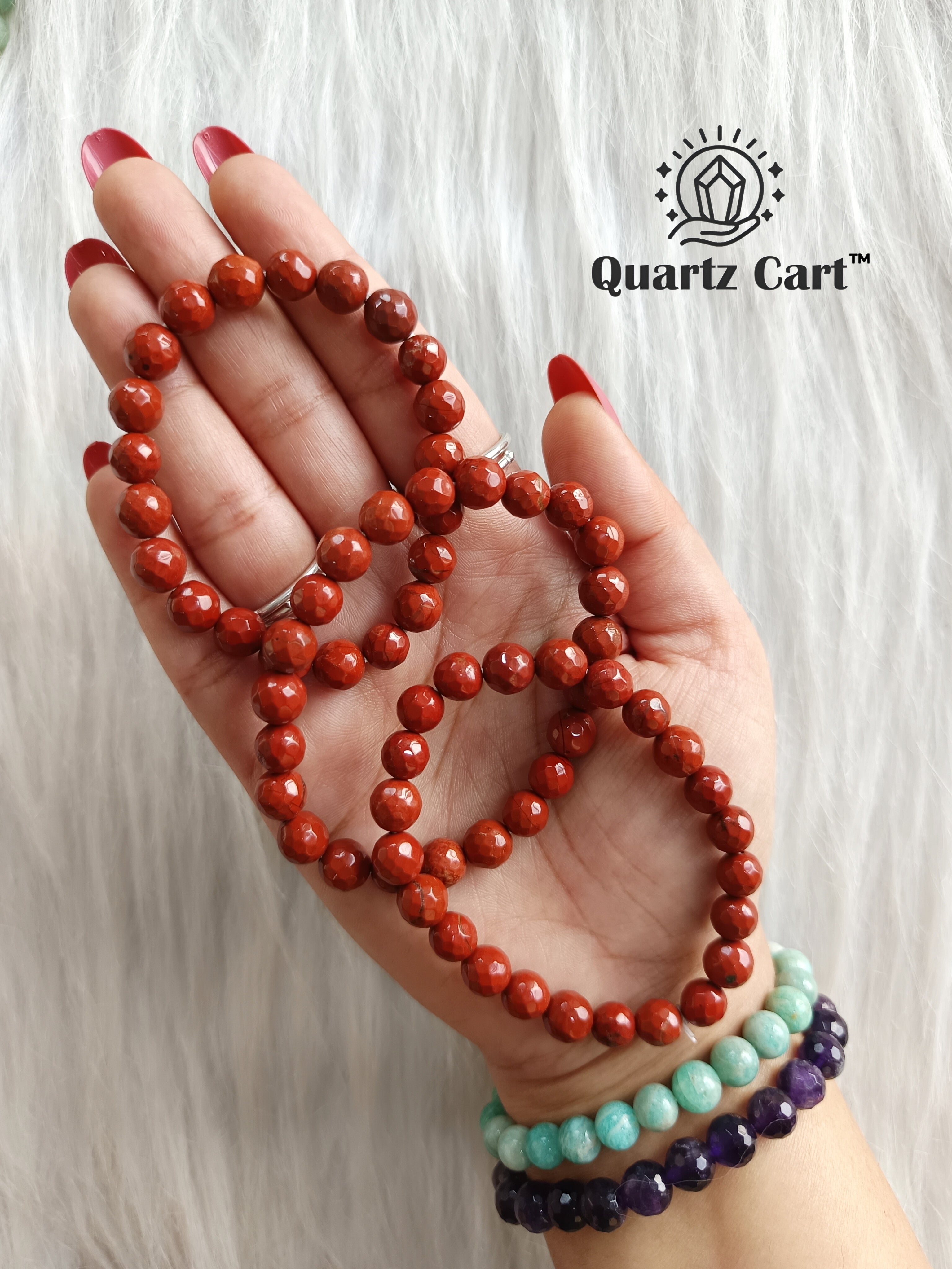 Hand holding Red Jasper faceted healing crystal bracelet for strength stability and grounding energy