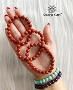Hand holding Red Jasper healing crystal bracelet for grounding strength protection and emotional balance