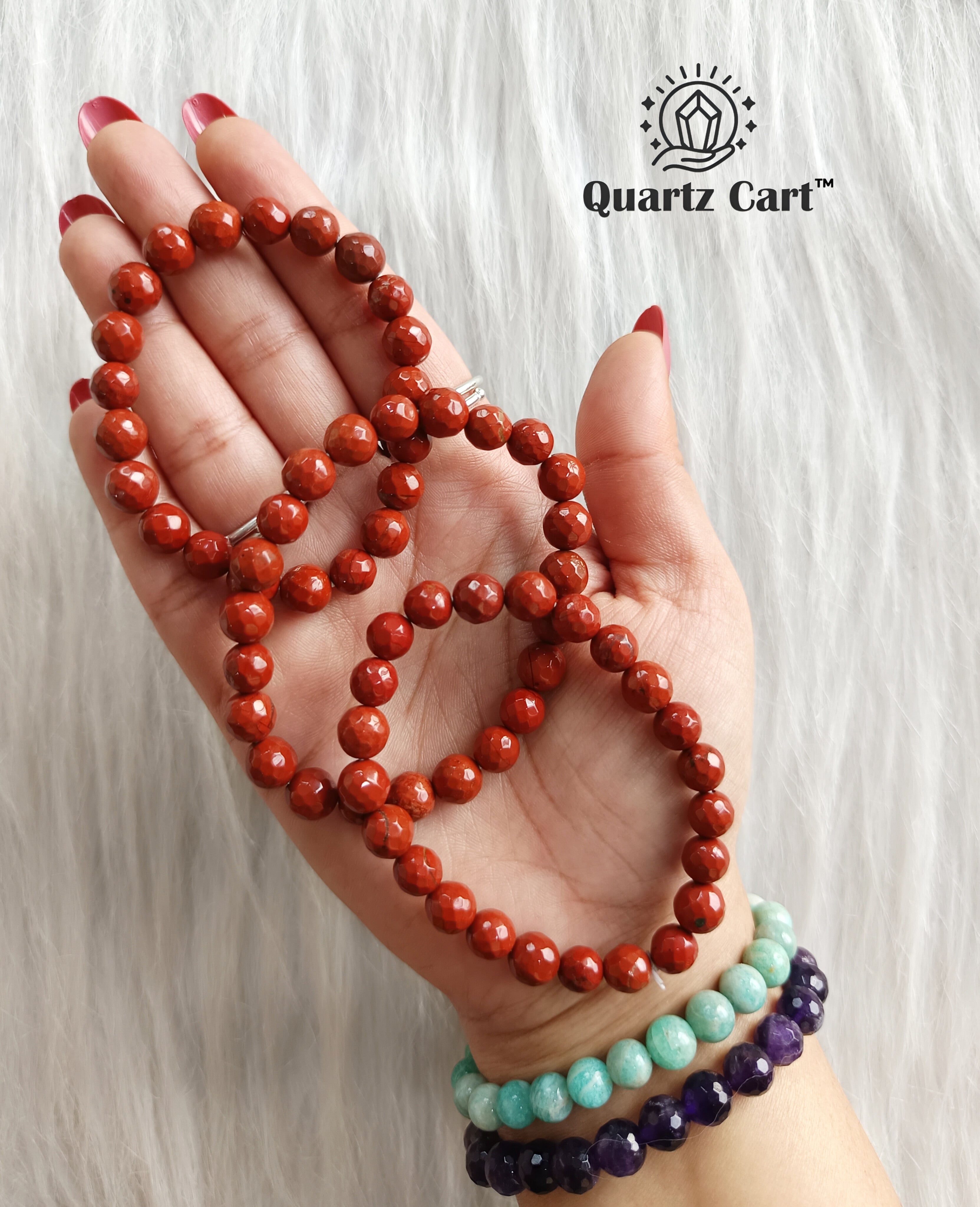 Hand holding Red Jasper healing crystal bracelet for grounding strength protection and emotional balance