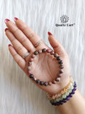 Rhodonite bracelet on hand showing natural pink and black gemstone beads for emotional healing and self love energy