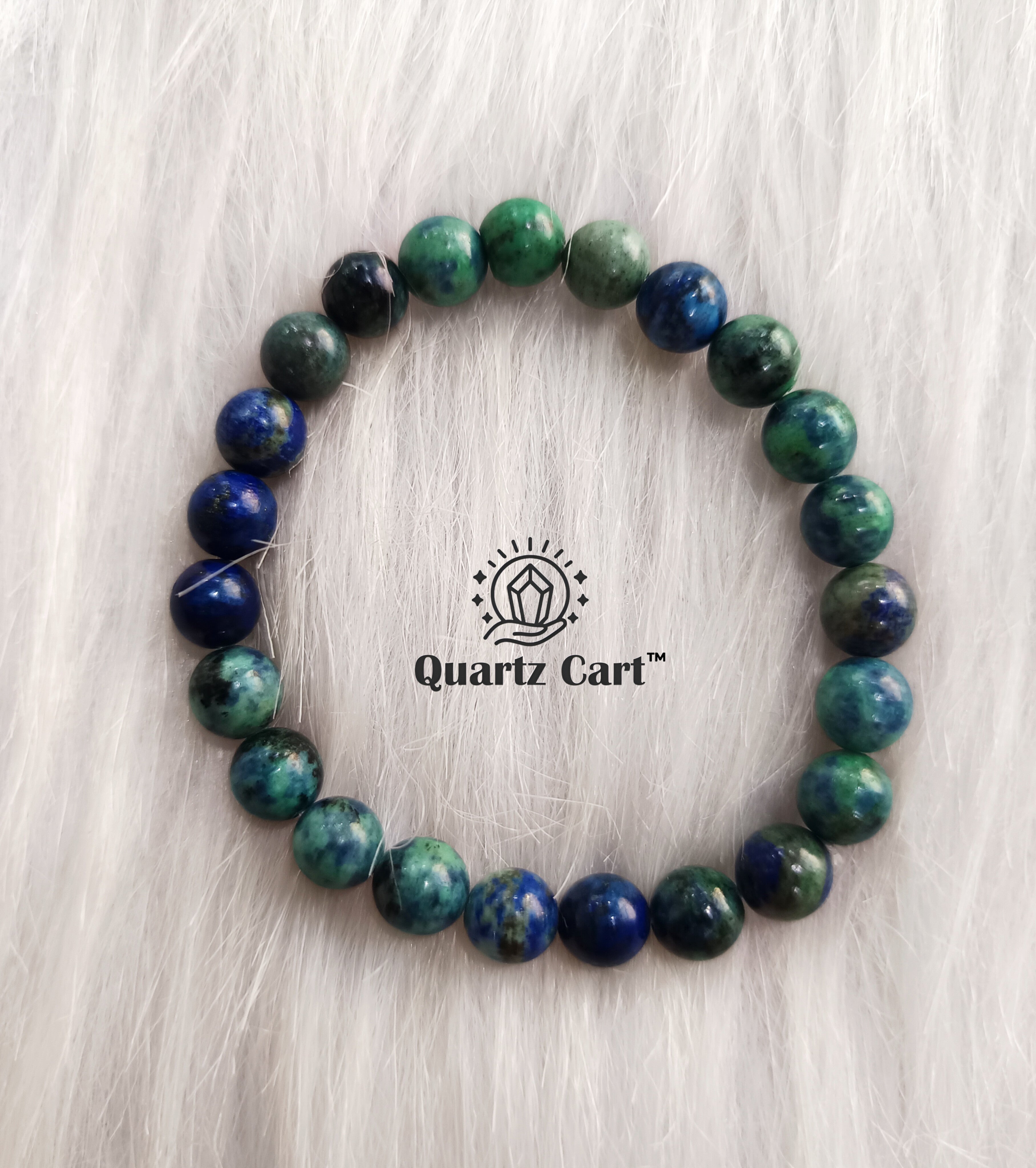 Beaded bracelet with blue and green stones on a light wooden surface, featuring the brand 'Quartz Cart'.
